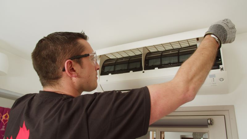 Contrat entretien chaudière, climatisation : technicien Abitibi en train d'assurer la maintenance d'une climatisation